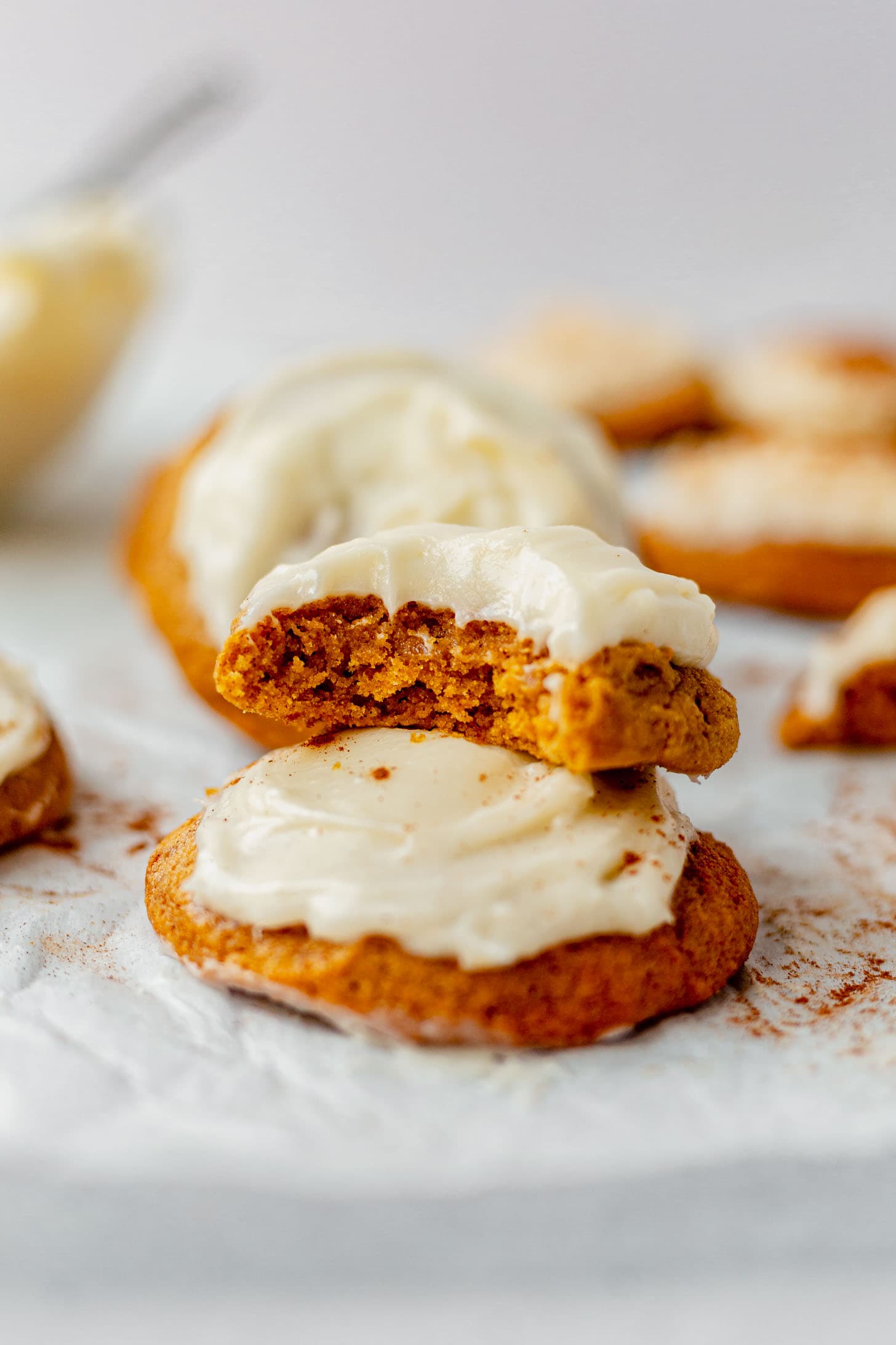 two pumpkin cookies stacked on a piece of parchment paper