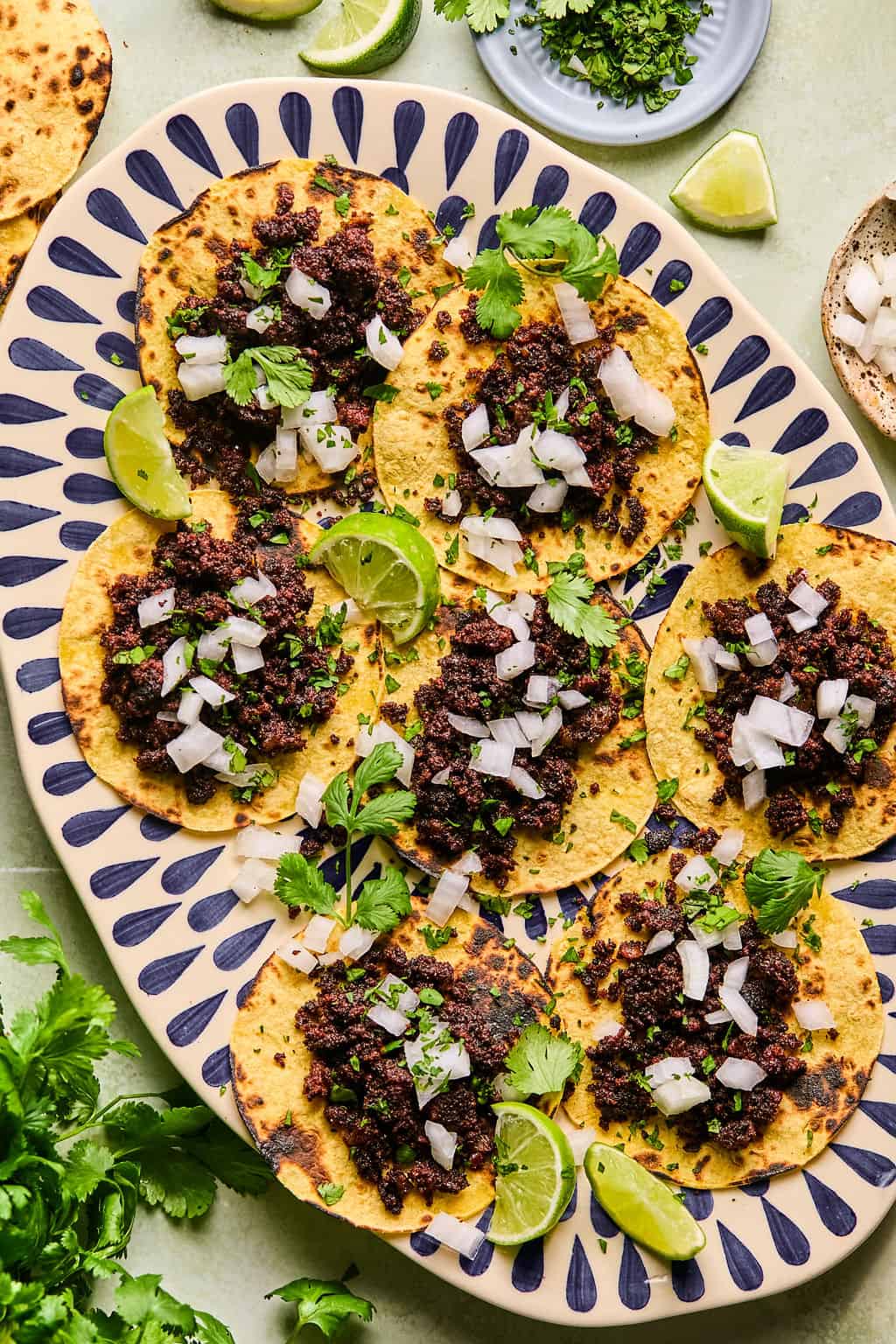 a plate of chorizo tacos with cilantro and onion.