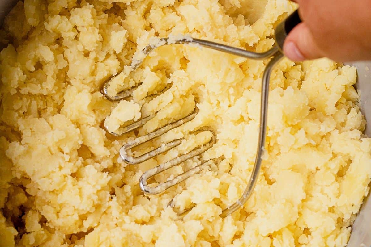 mashing yukon gold potatoes with a potato masher