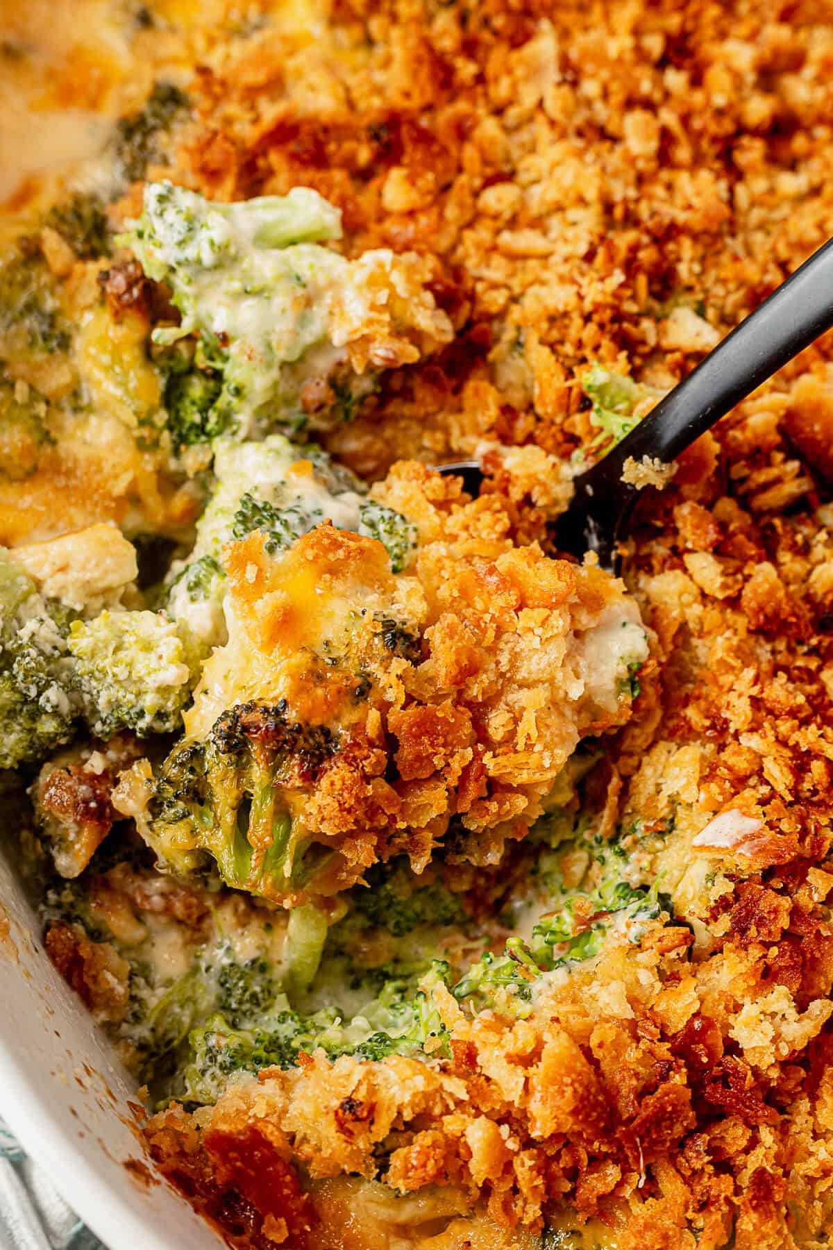 a serving spoon scooping broccoli casserole out of the casserole dish