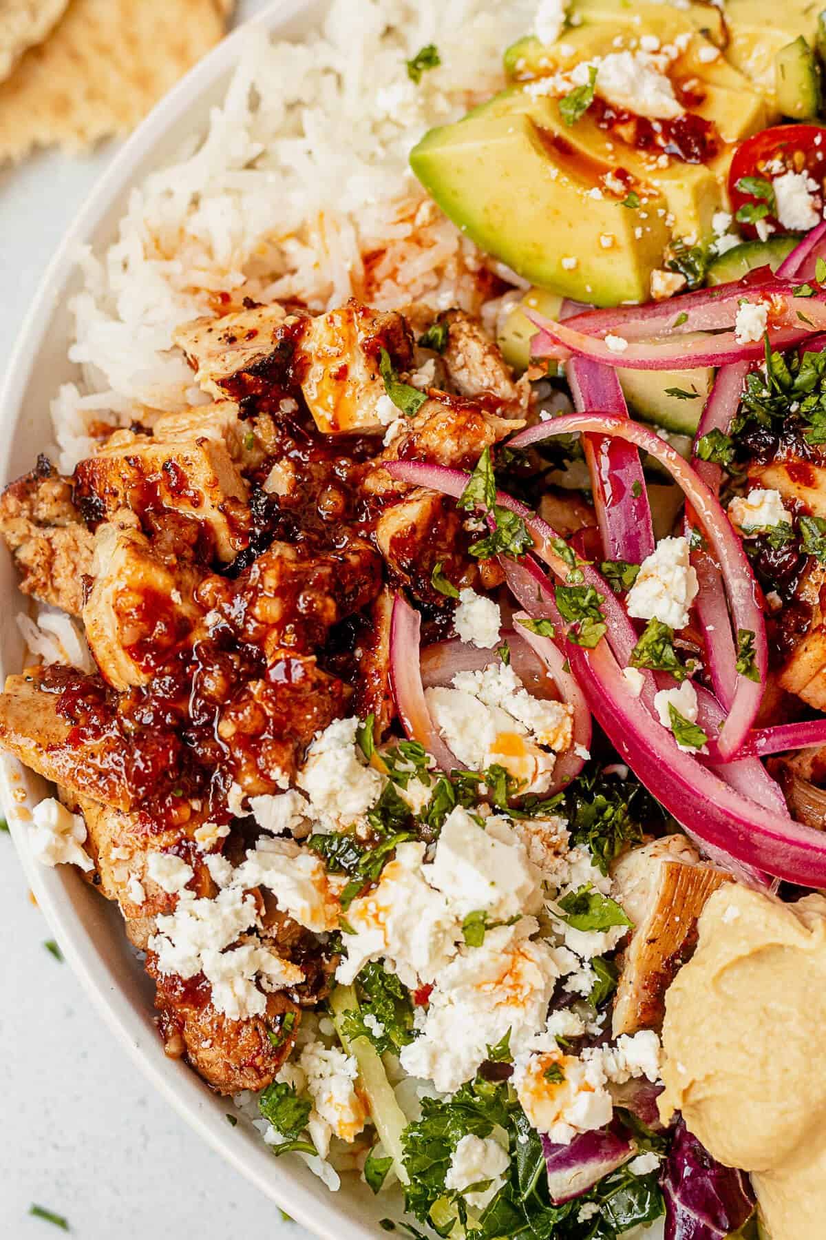 honey harissa chicken on top of rice and greens and covered in harissa vinaigrette