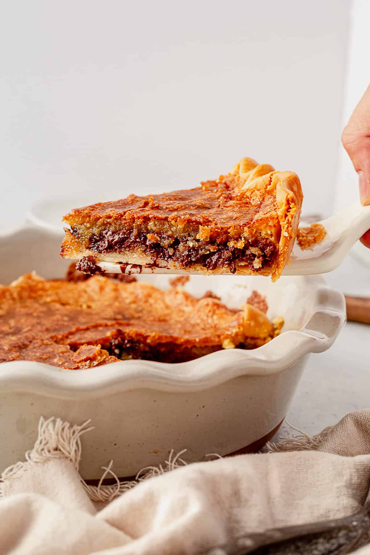 a piece of freshly baked warm chocolate chip pie on a pie spatula coming out of the pie