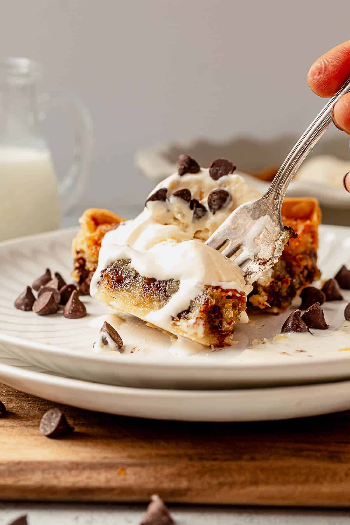 a large bite of chocolate chip pie and melted vanilla ice cream on a fork