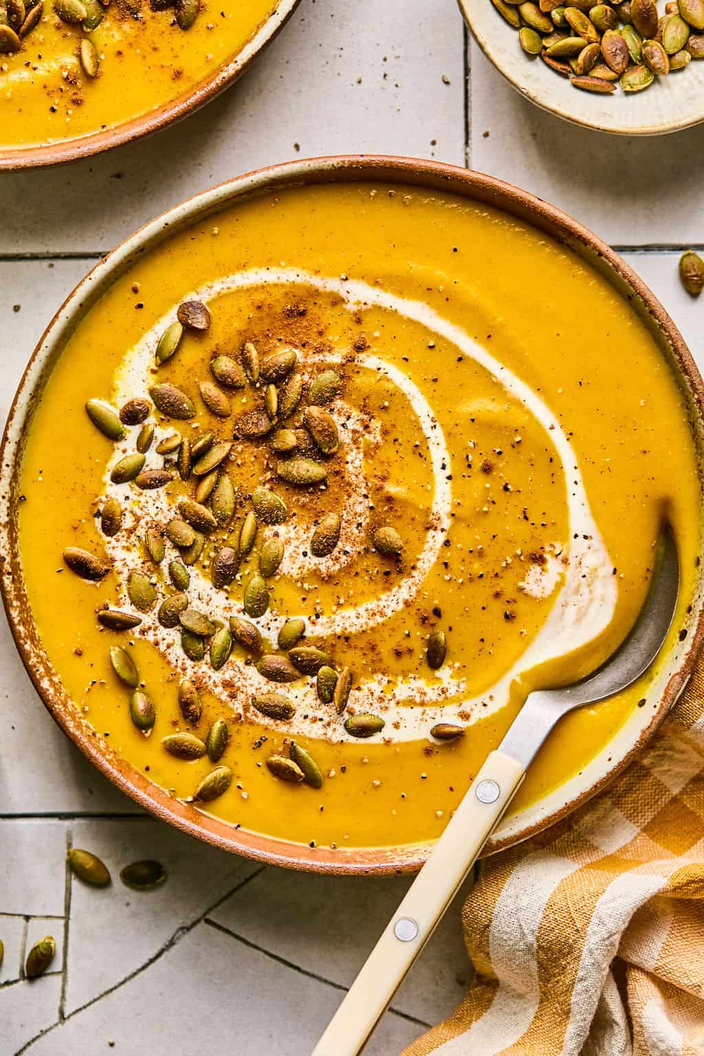 a bowl of homemade panera autumn squash soup in a bowl with a spoon.