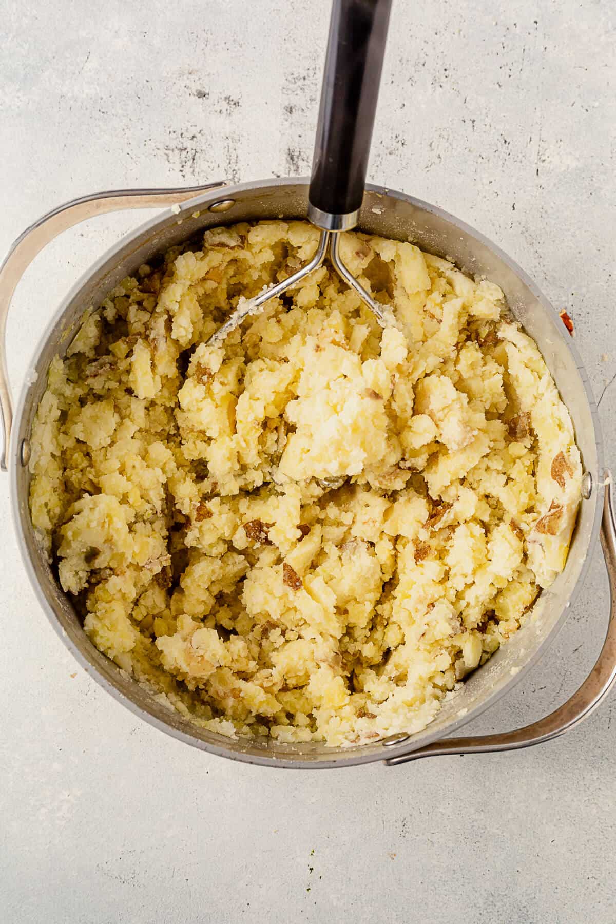 potatoes being mashed with a potato mashed in a pot