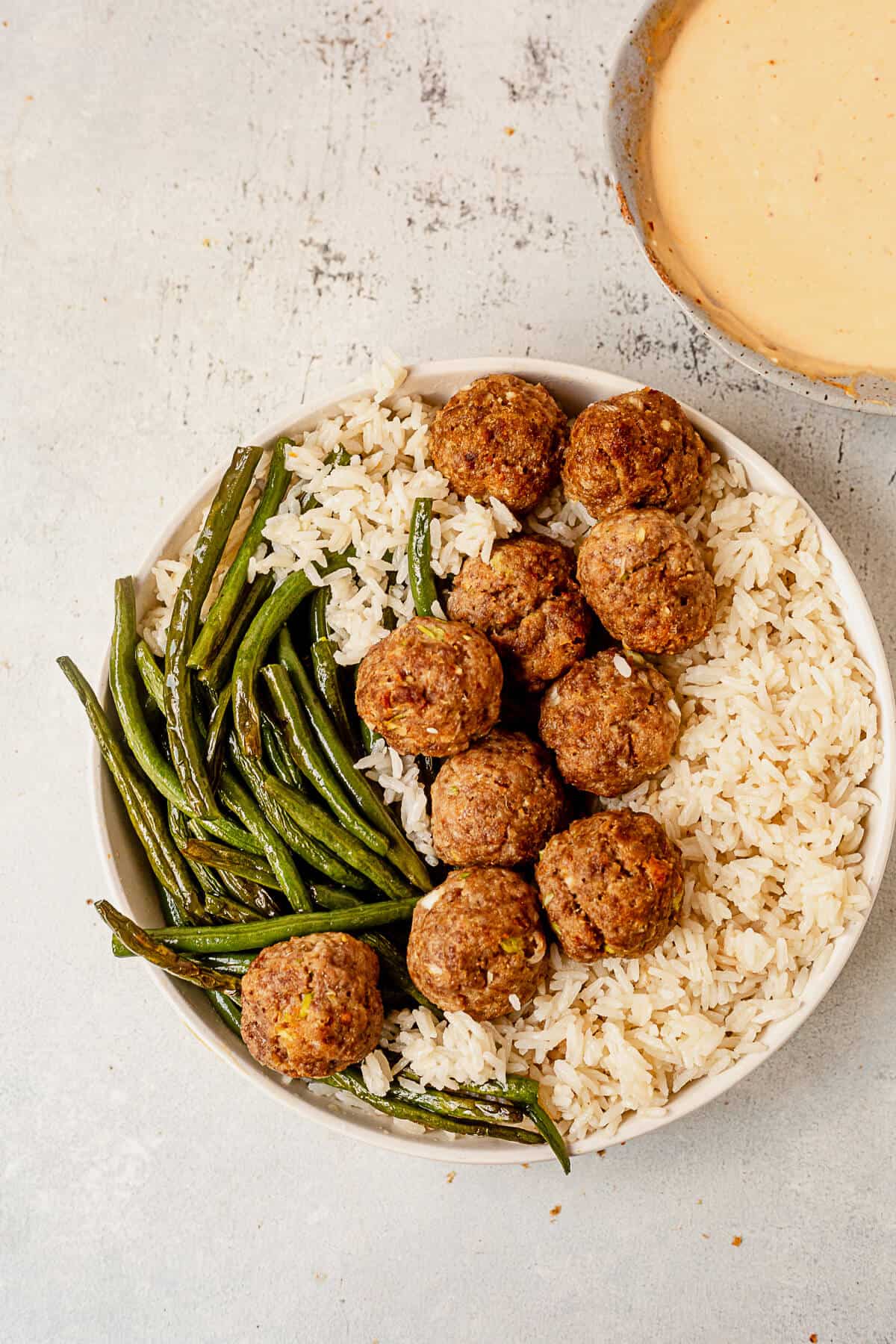 a bowl of rice, green beans and asian meatballs