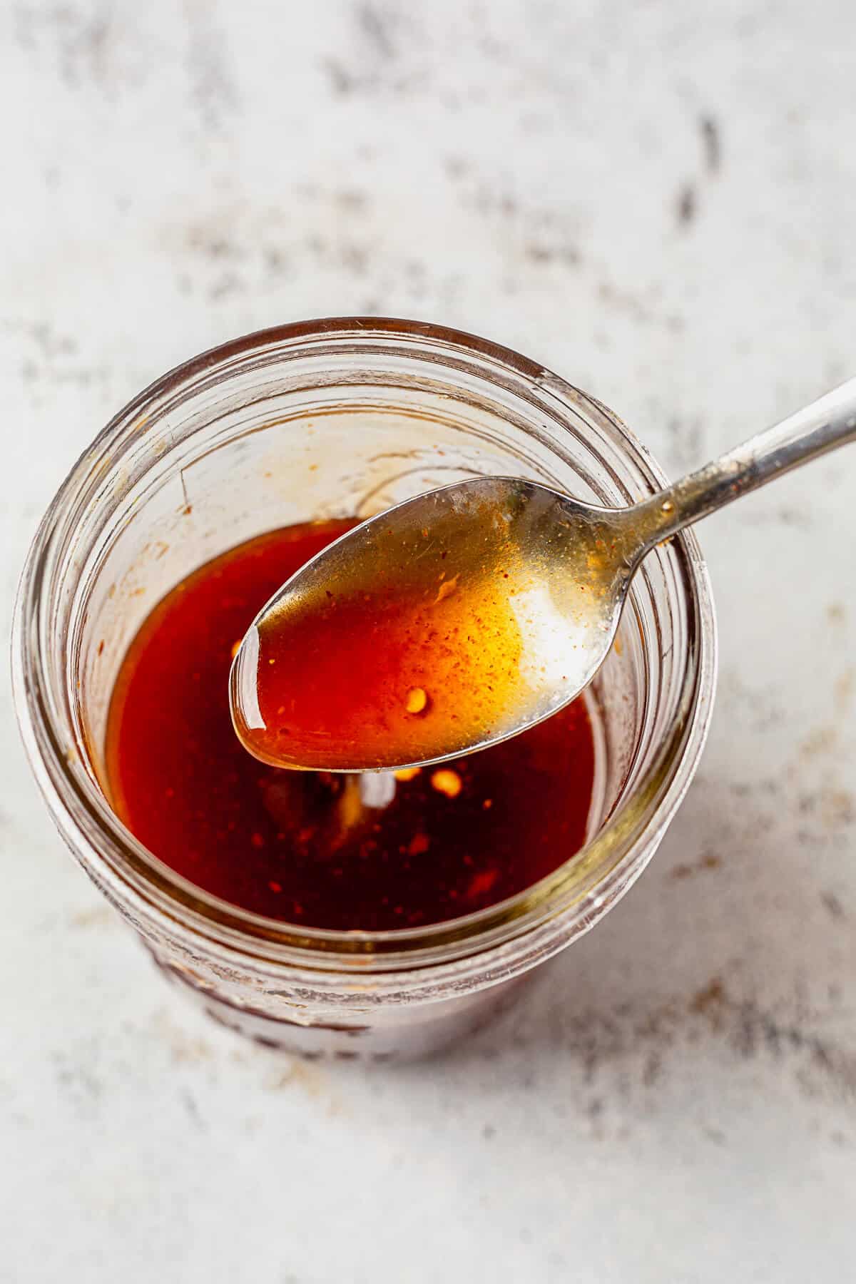 a spoonful of firecracker sauce coming out of a jar