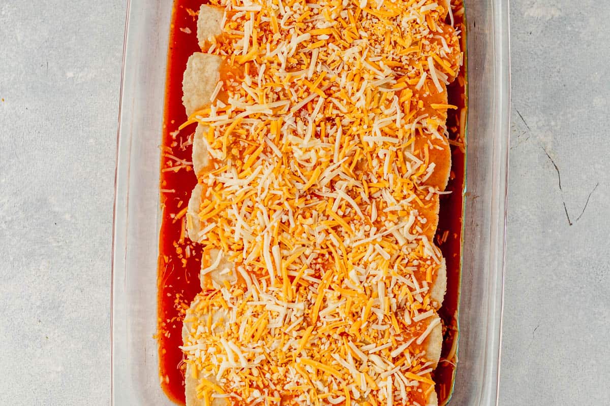 unbaked ground turkey enchiladas in a casserole dish with shredded cheese on top