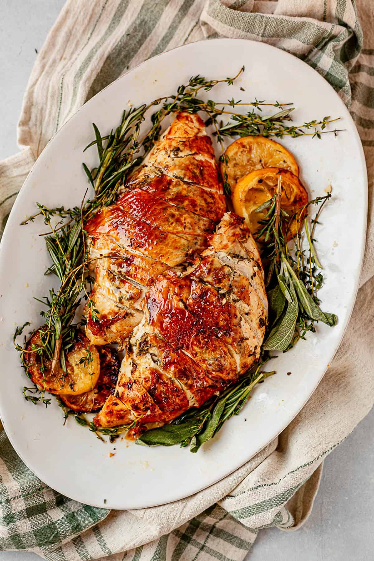 roasted turkey breasts on a serving platter with herbs