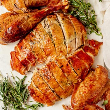 roasted turkey legs and breasts on a serving tray with herbs
