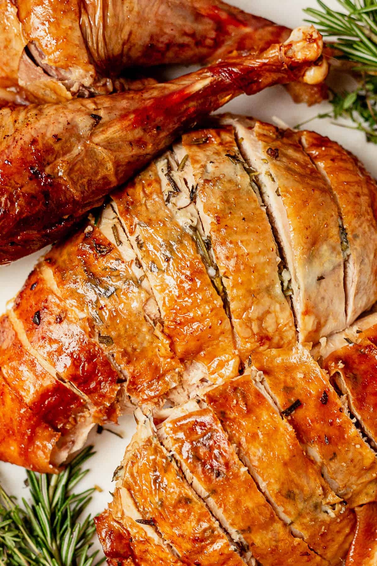 sliced roasted turkey breast next to roasted turkey legs on a platter