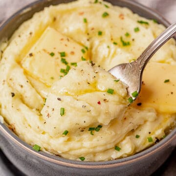 a fork scooping out mashed potatoes from a bowl