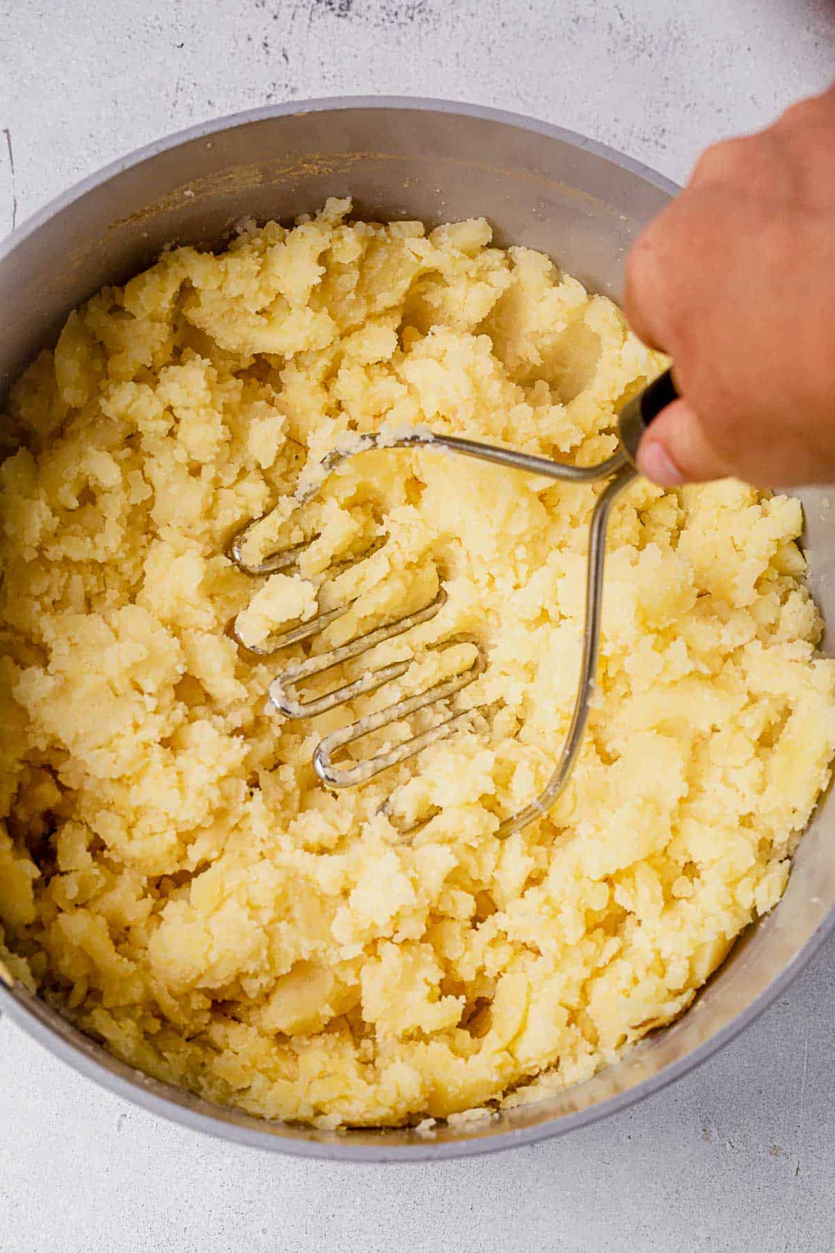 mashing potatoes in a pot