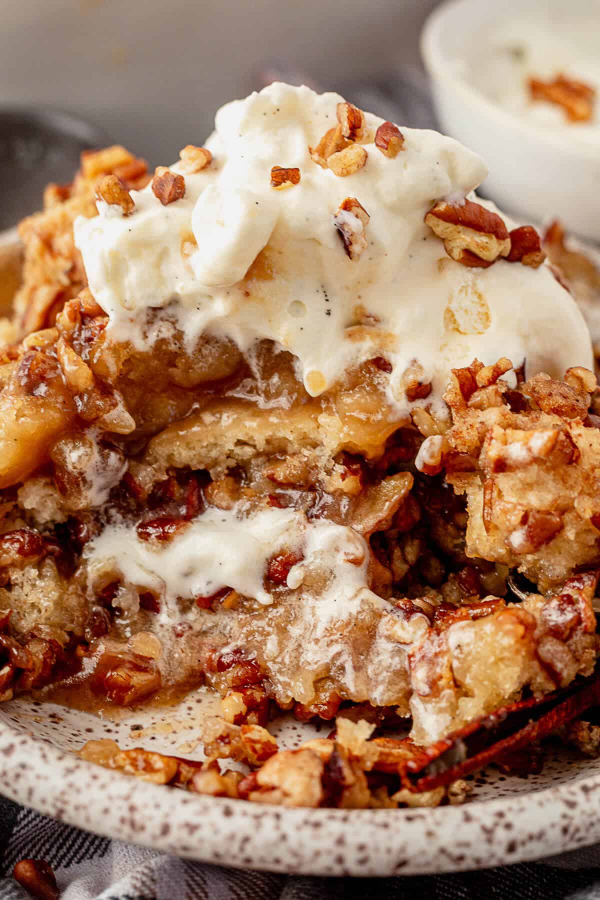 a large serving of pecan pie cobbler on a plate with homemade whipped cream