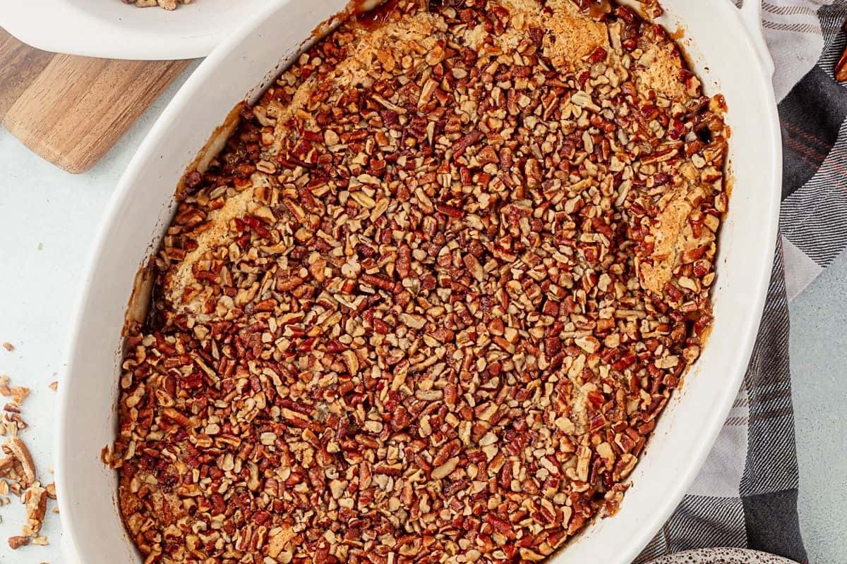 freshly baked pecan pie cobbler in a white casserole dish with gooey bubbling edges