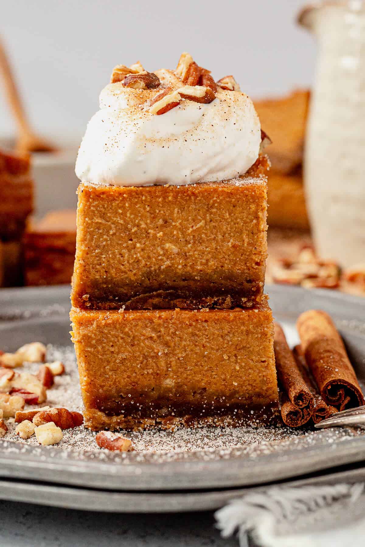 two pumpkin pie bars stacked with whipped cream