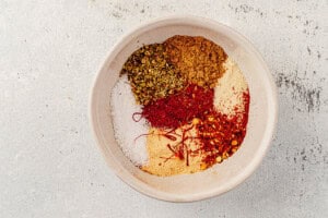 Bowl filled with a colorful blend of paprika, oregano, saffron, salt, and other spices for Spanish chicken and rice.