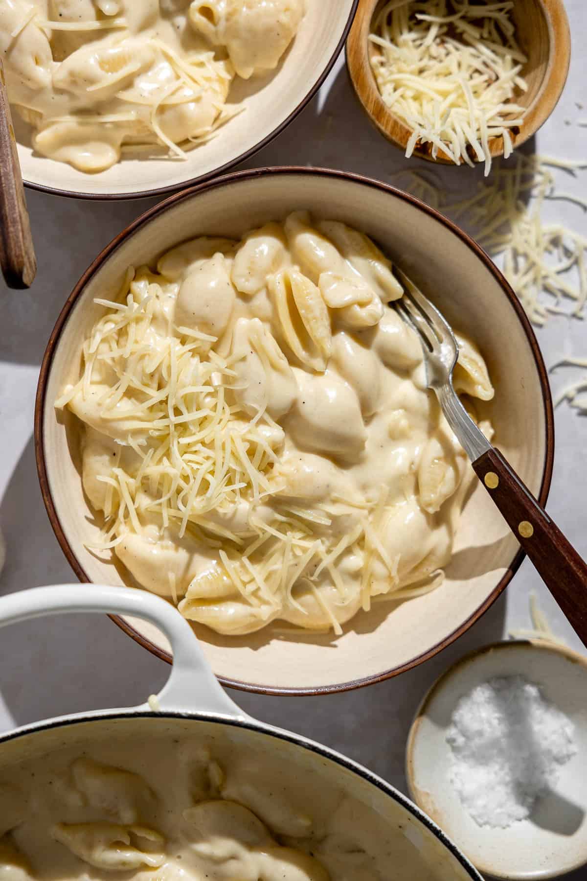 a bowl of white cheddar mac and cheese with shredded cheese on top.