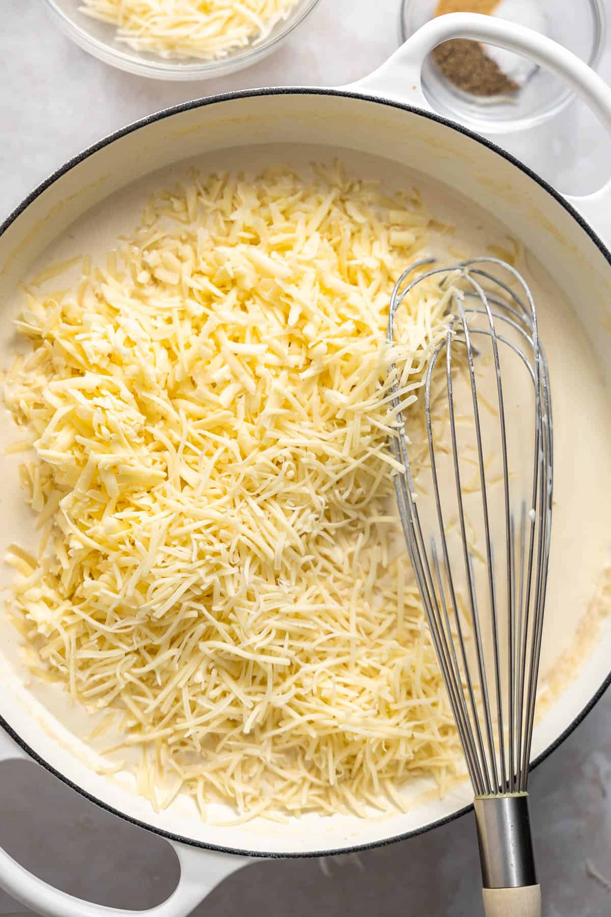 shredded white cheese melting into mac and cheese sauce.