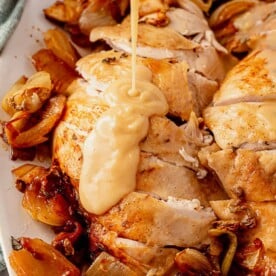 pouring gluten-free gravy onto golden roasted turkey breast