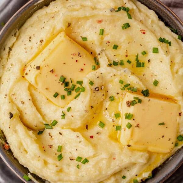 a bowl of boursin mashed potatoes topped with butter and chives.