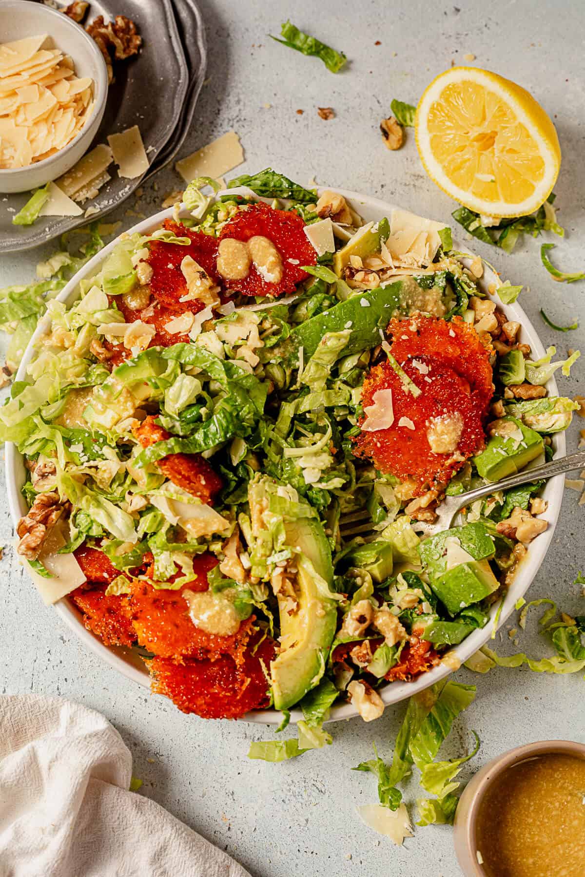 brussels sprout caesar salad with avocado, sweet potatoes, and parmesan cheese