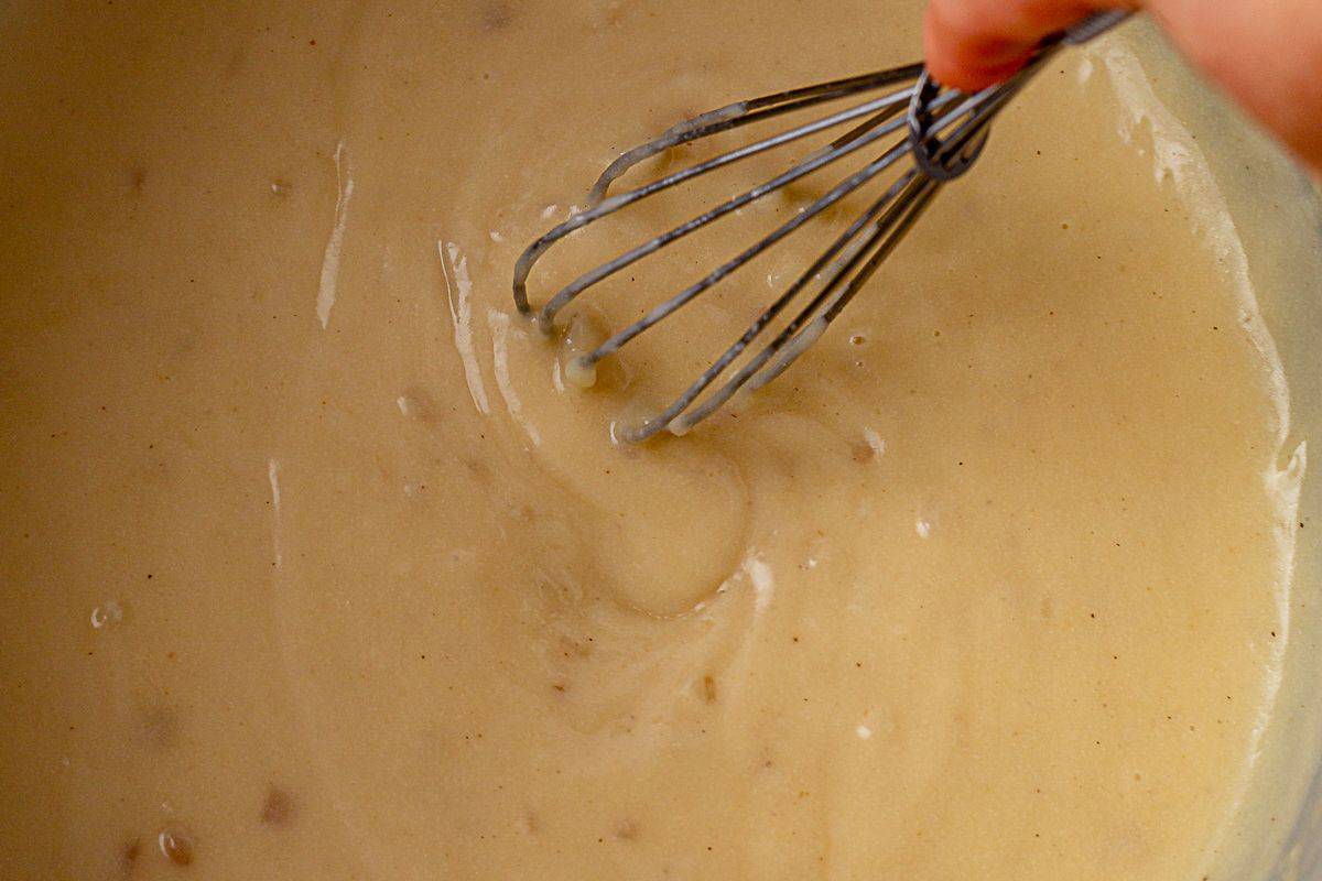 whisking a gravy base of butter, gluten free flour and broth in a pot