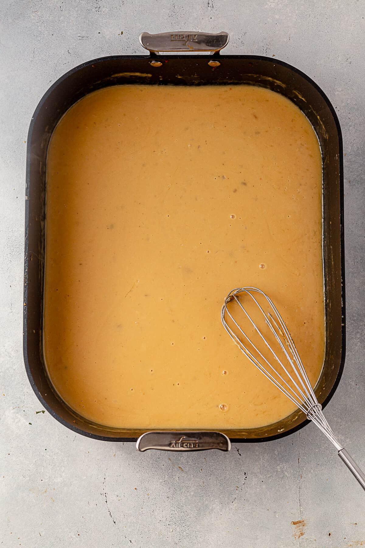 whisking gluten free gravy in a roasting pan.