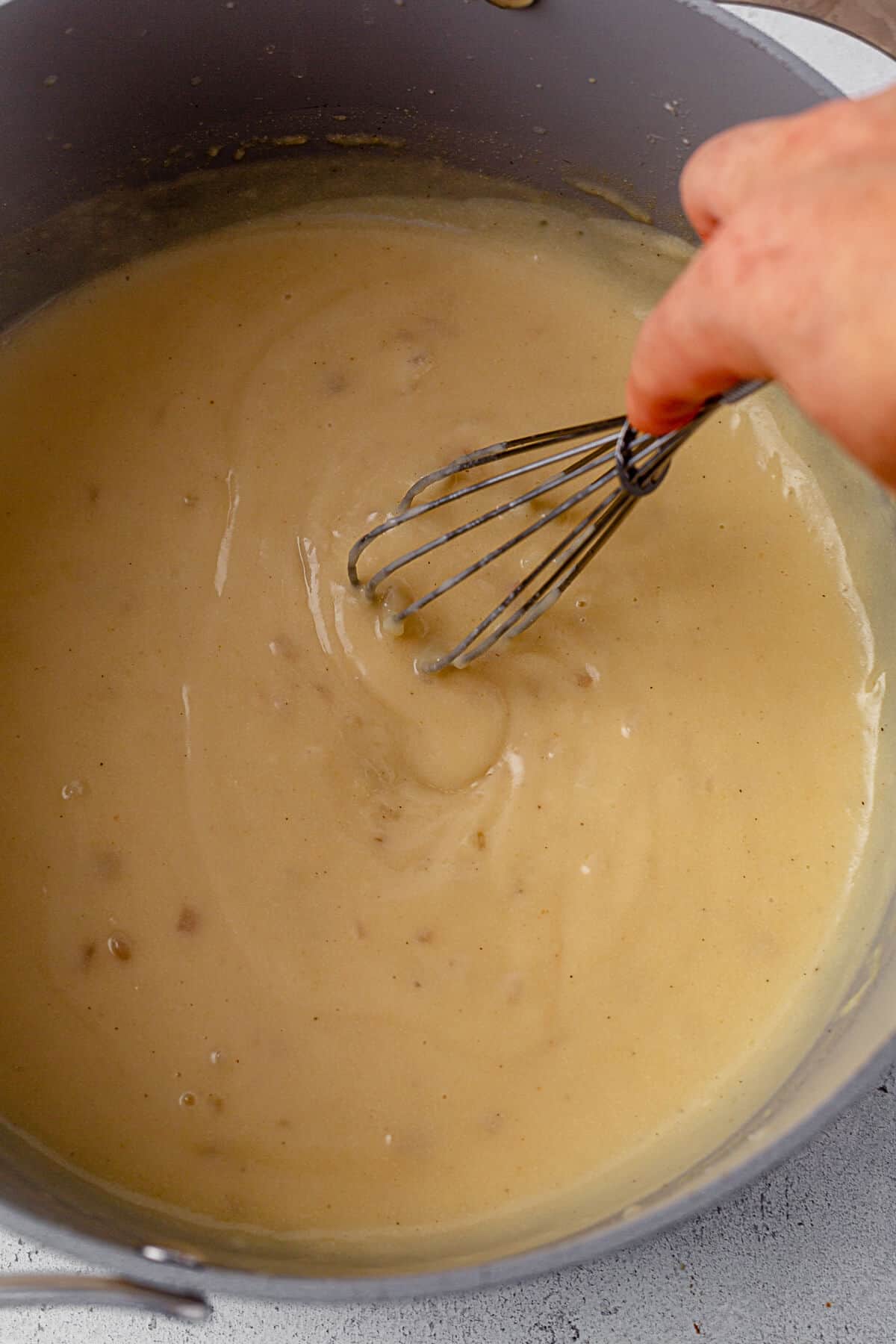 whisking broth into a roux to create a gravy thickener.