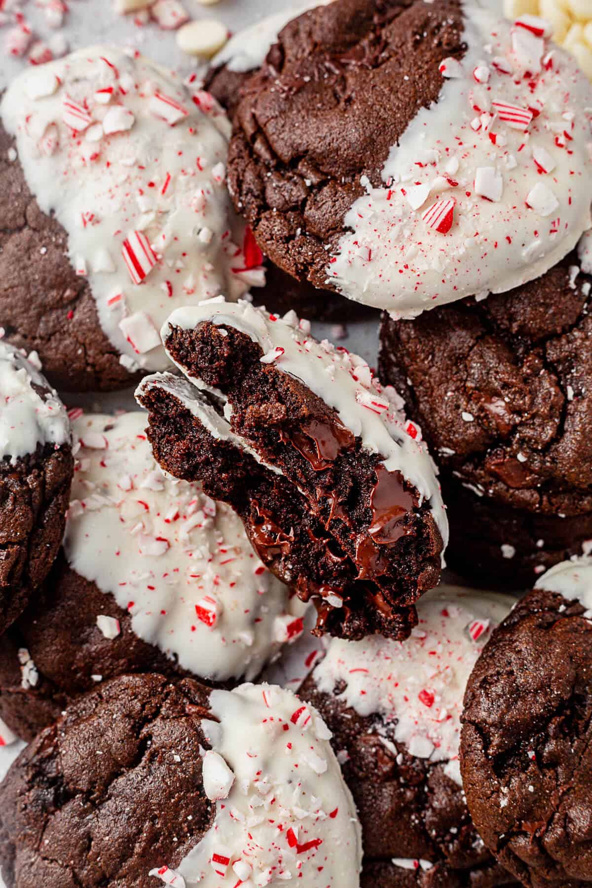 a chocolate peppermint cookie broken in half with a plate of more cookies