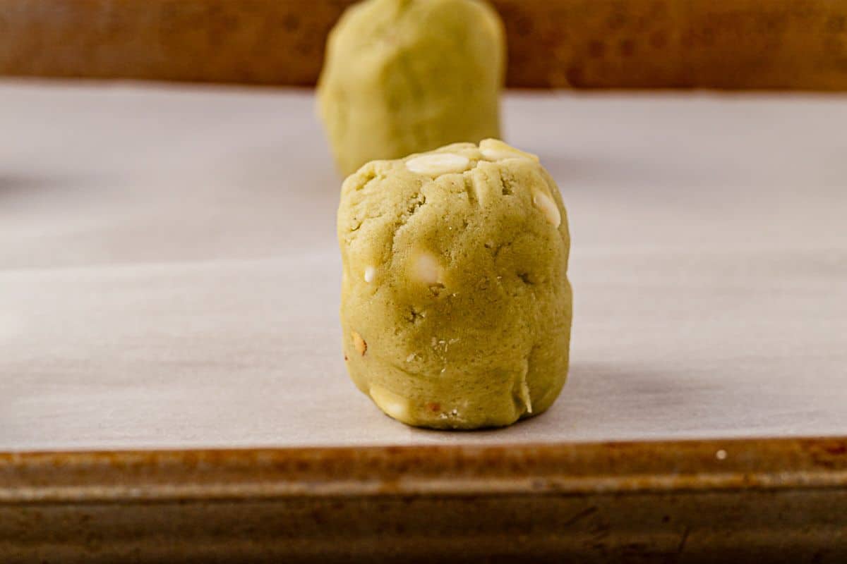 pistachio pudding cookie dough ball on a parchment lined cookie sheet