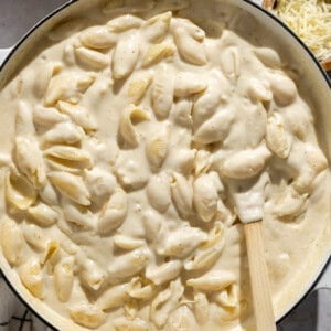 white cheddar mac and cheese recipe on the stove top with a spatula.