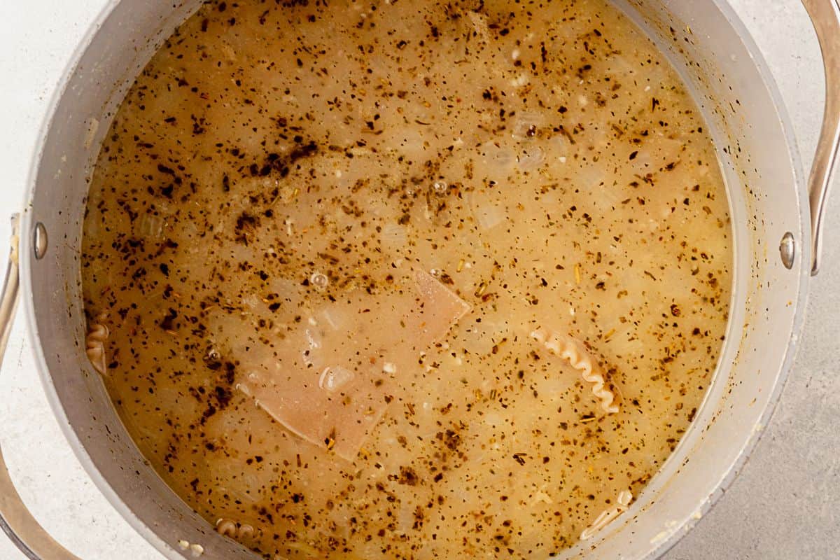 broken lasagna noodles cooking in a pot of lasagna soup broth