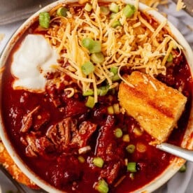 slow cooker beef stew with cornbread, cheese, onion, and sour cream