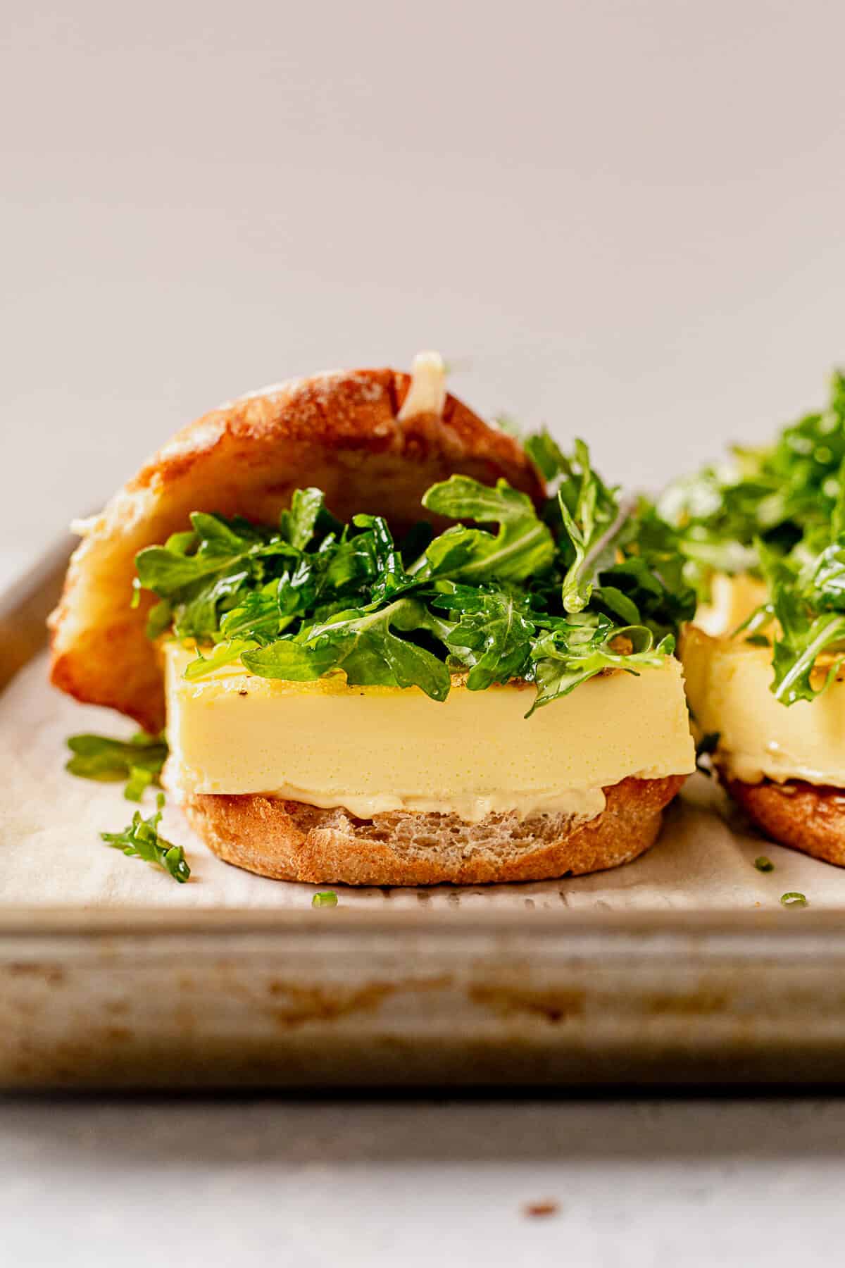 fluffy souffled eggs on a bun with greens and melted cheese