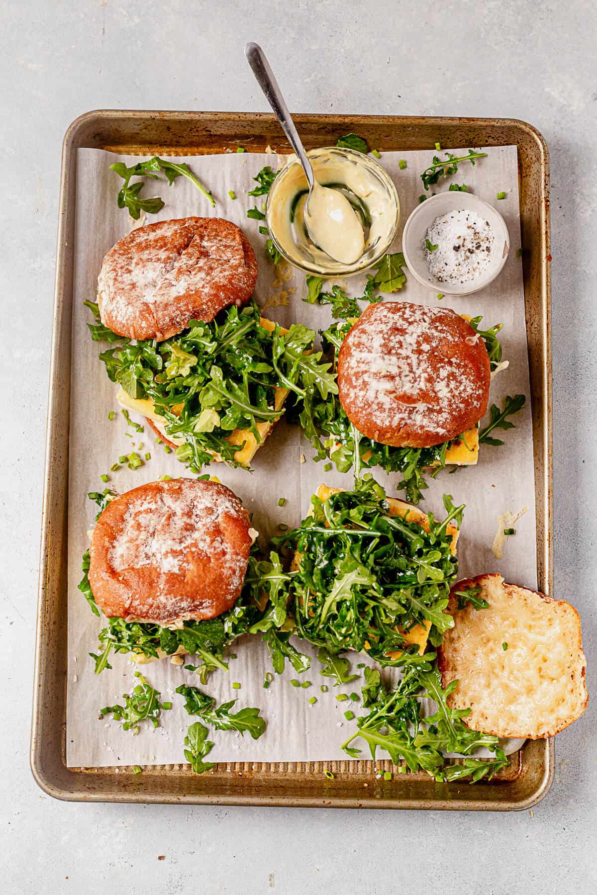 four egg sandwiches with cheese and arugula on a serving platter