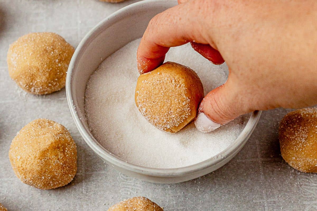 rolling a peanut butter cookie dough ball in sugar