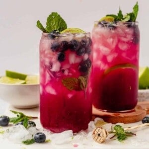 two blueberry mojitos with crushed ice on a countertop