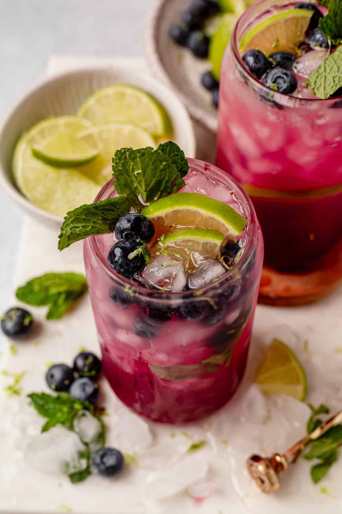 lime, mint, and blueberries garnished on top of a blueberry mojito