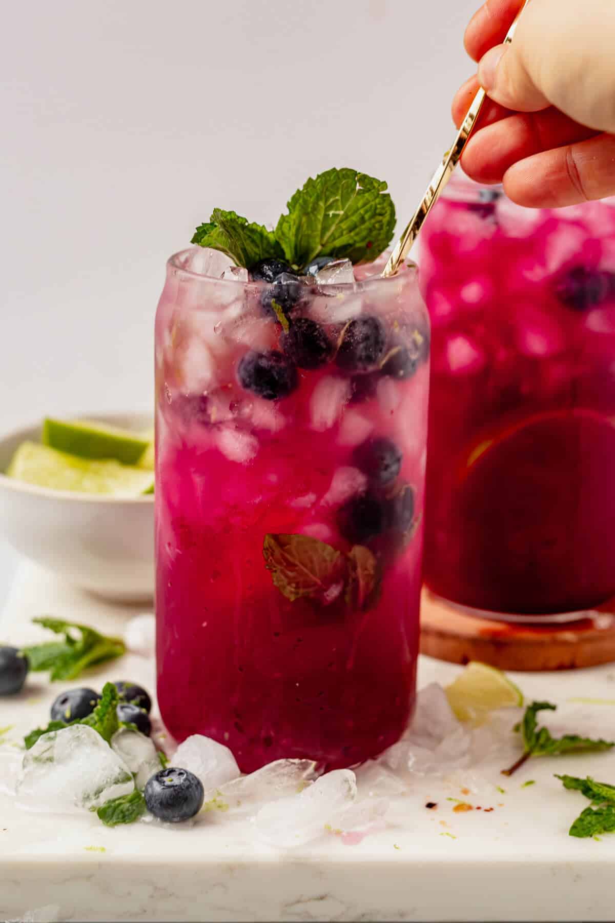 stirring club soda into a blueberry mojito