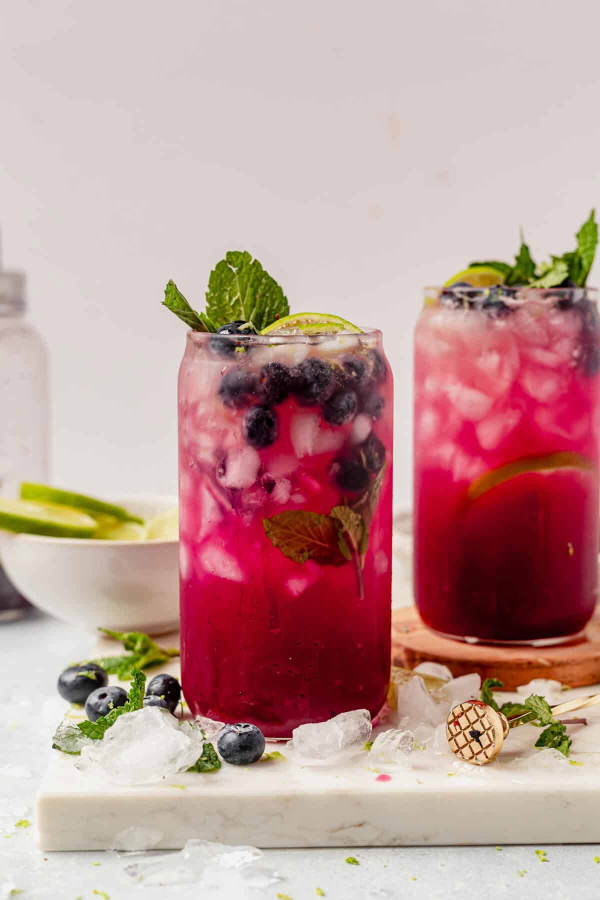 two blueberry mojitos with fresh lime, fresh mint, and blueberries