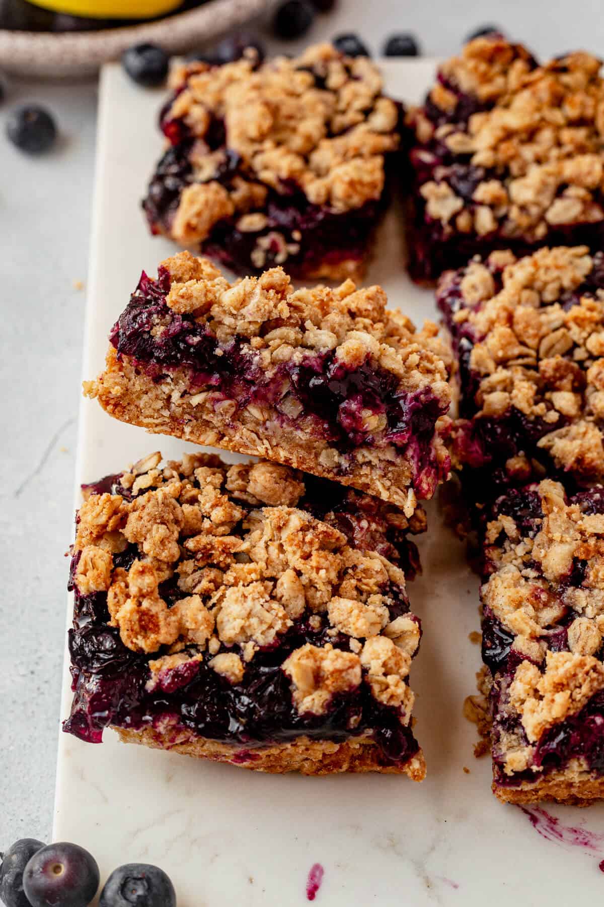 gooey blueberry filling coming out of the sides of oatmeal crumb bars