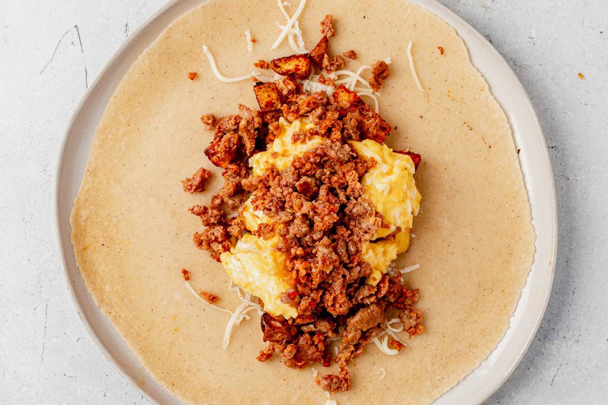 breakfast potatoes, scrambled eggs, chorizo, and cheese in a burrito
