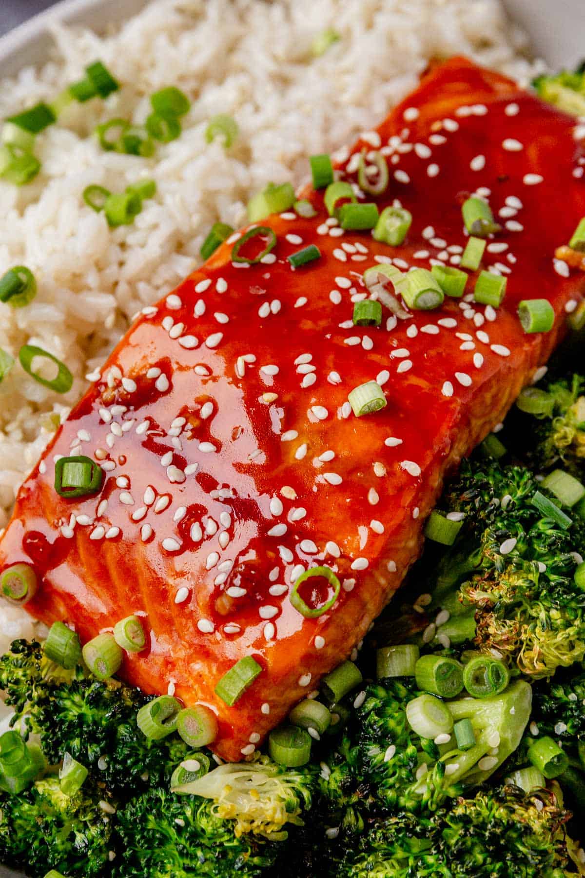 green onions on top of a piece of a honey sriracha salmon filet
