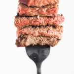 a fork stabbed into five different pieces of beef, all cooked to a different doneness
