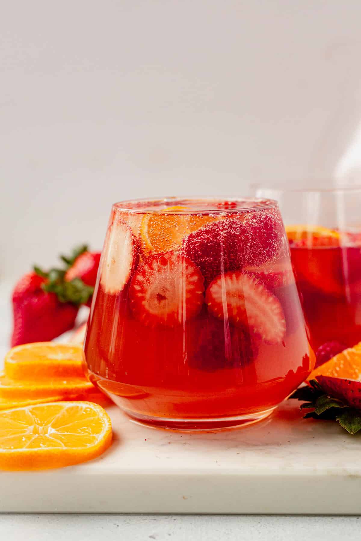 a wine glass full of moscato sangria, strawberries, oranges, and bubble soda water
