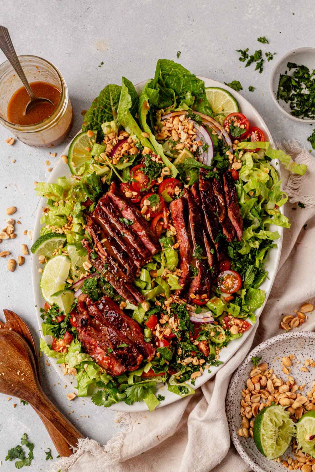 thai steak salad on a serving dish with peanuts, onions, tomatoes, and cilantro