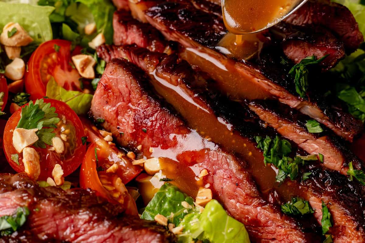 drizzling thai dressing over thinly sliced steak
