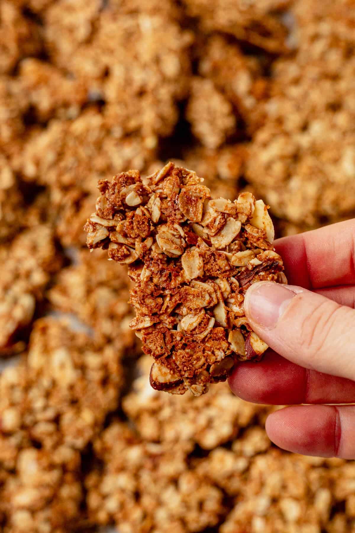 holding a large golden brown cluster of homemade granola