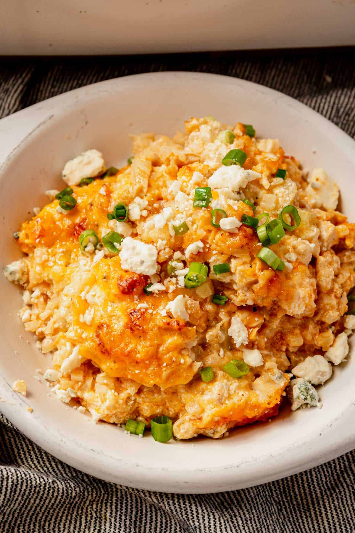 buffalo chicken casserole with blue cheese and green onions in a dish